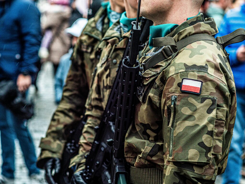 Close-up of Polish soldiers in camouflaged uniforms standing in line during a public event.